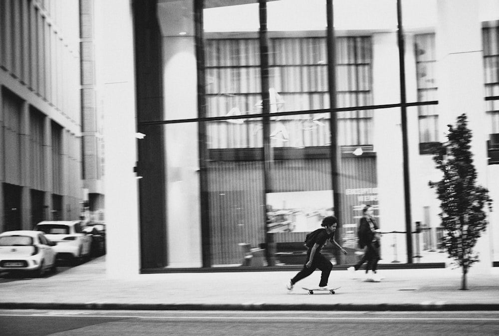 grayscale photo of woman walking on sidewalk