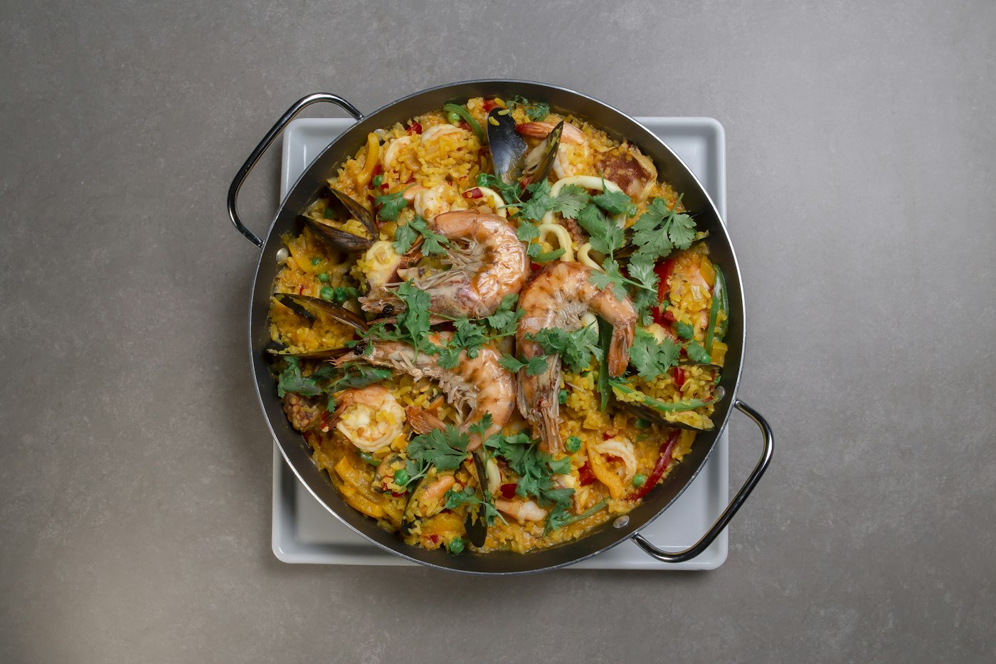 A pan of Spanish seafood paella cooking over a flame