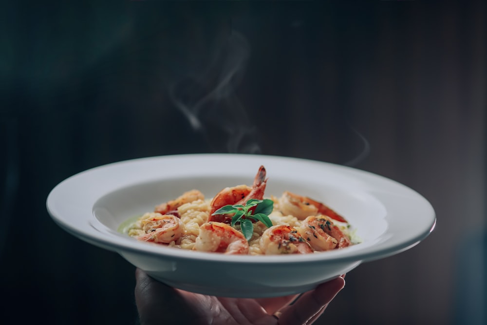 person holding white ceramic bowl with food