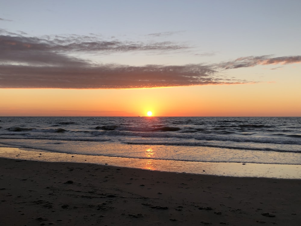 sea waves crashing on shore during sunset