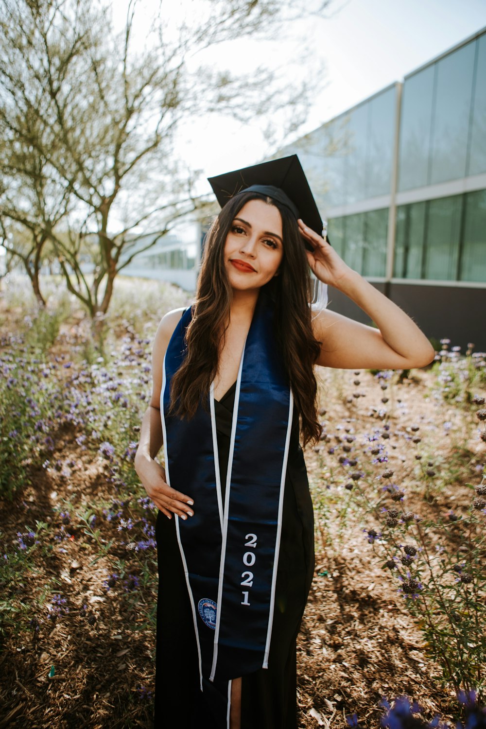 woman in black academic dress and black academic hat standing on brown leaves during daytime