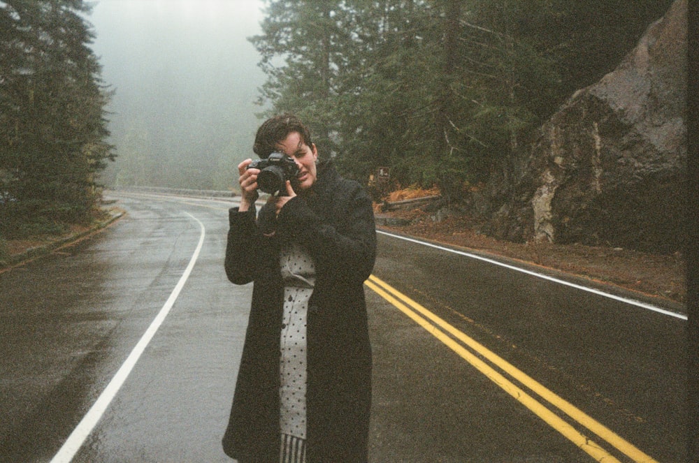 femme en manteau noir debout sur la route