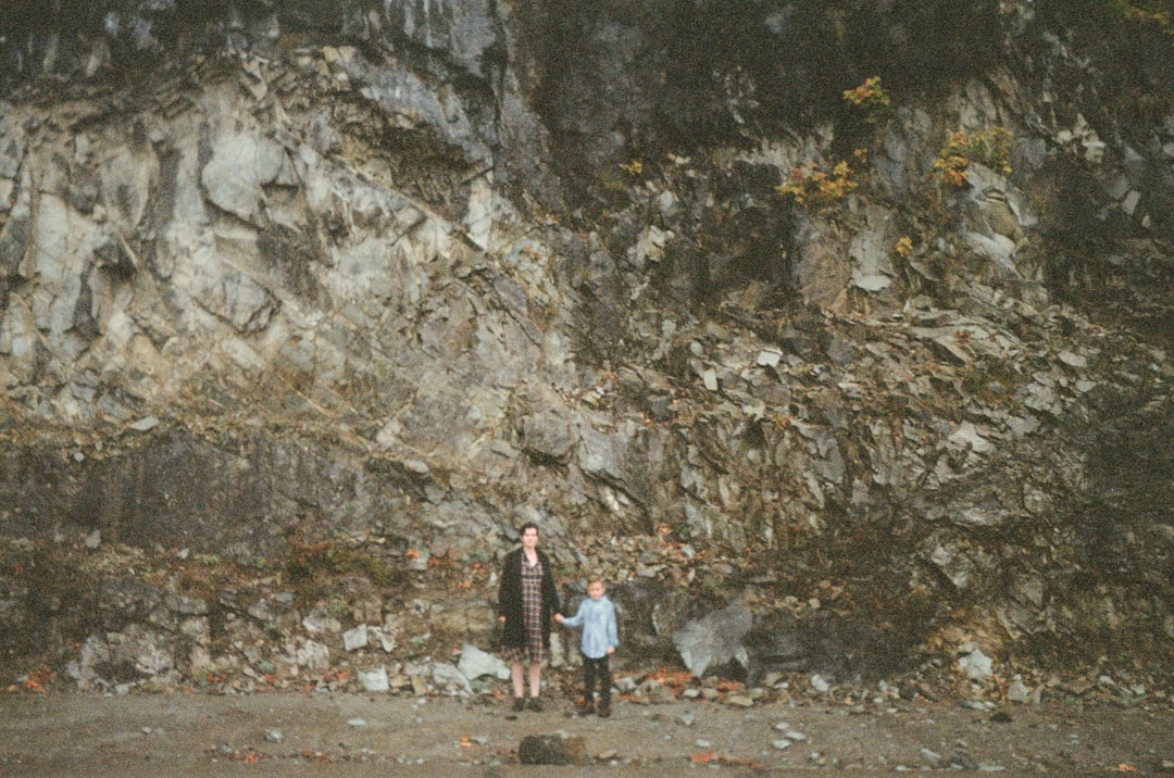 woman in white and red dress standing near gray rock formation during daytime