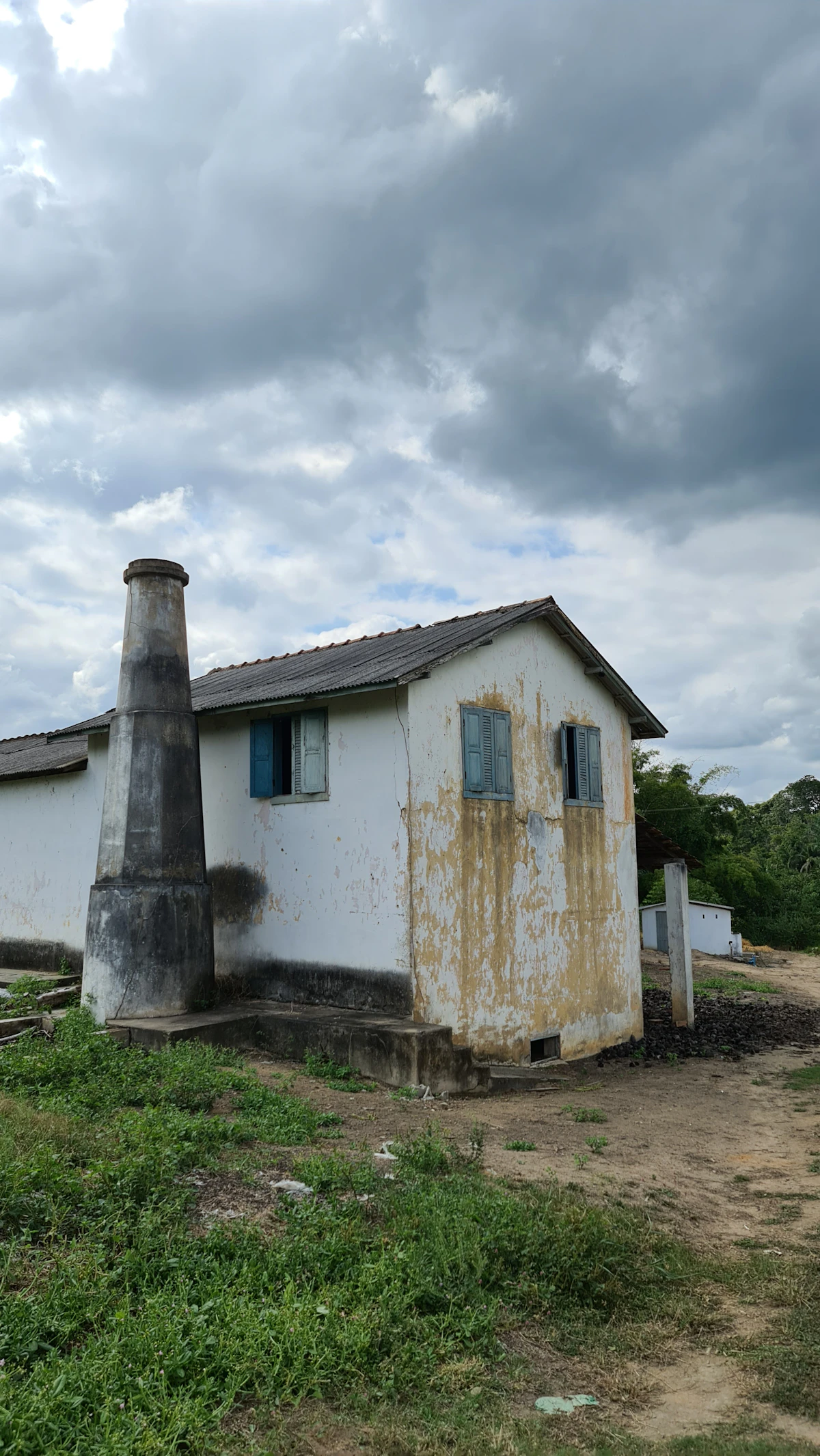 Rumah beton putih di atas lahan rumput di bawah langit berawan