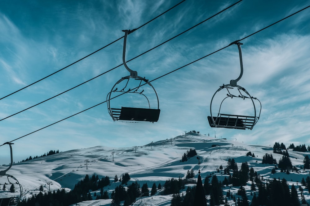 cable cars over snow covered ground under blue sky during daytime