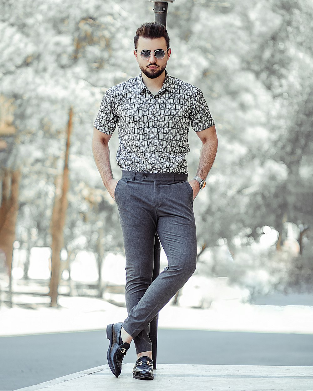 man in black and white polka dot shirt and blue denim jeans standing on gray concrete