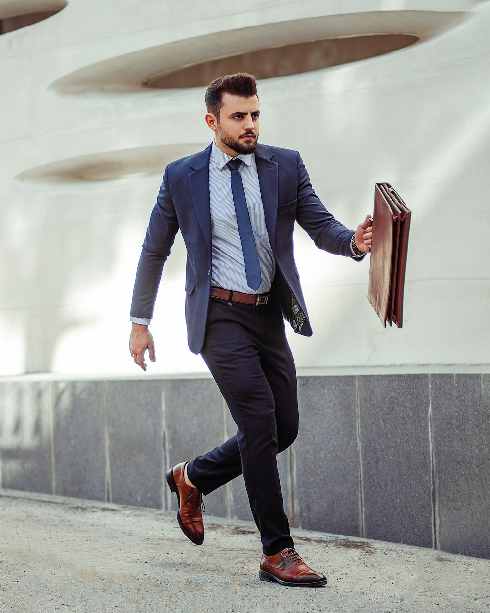 man in blue dress shirt and black pants standing on gray concrete stairs