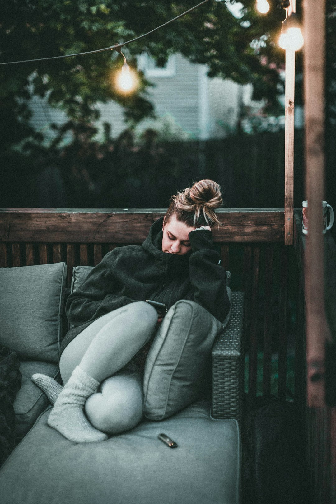 woman in black jacket and gray pants sitting on gray couch