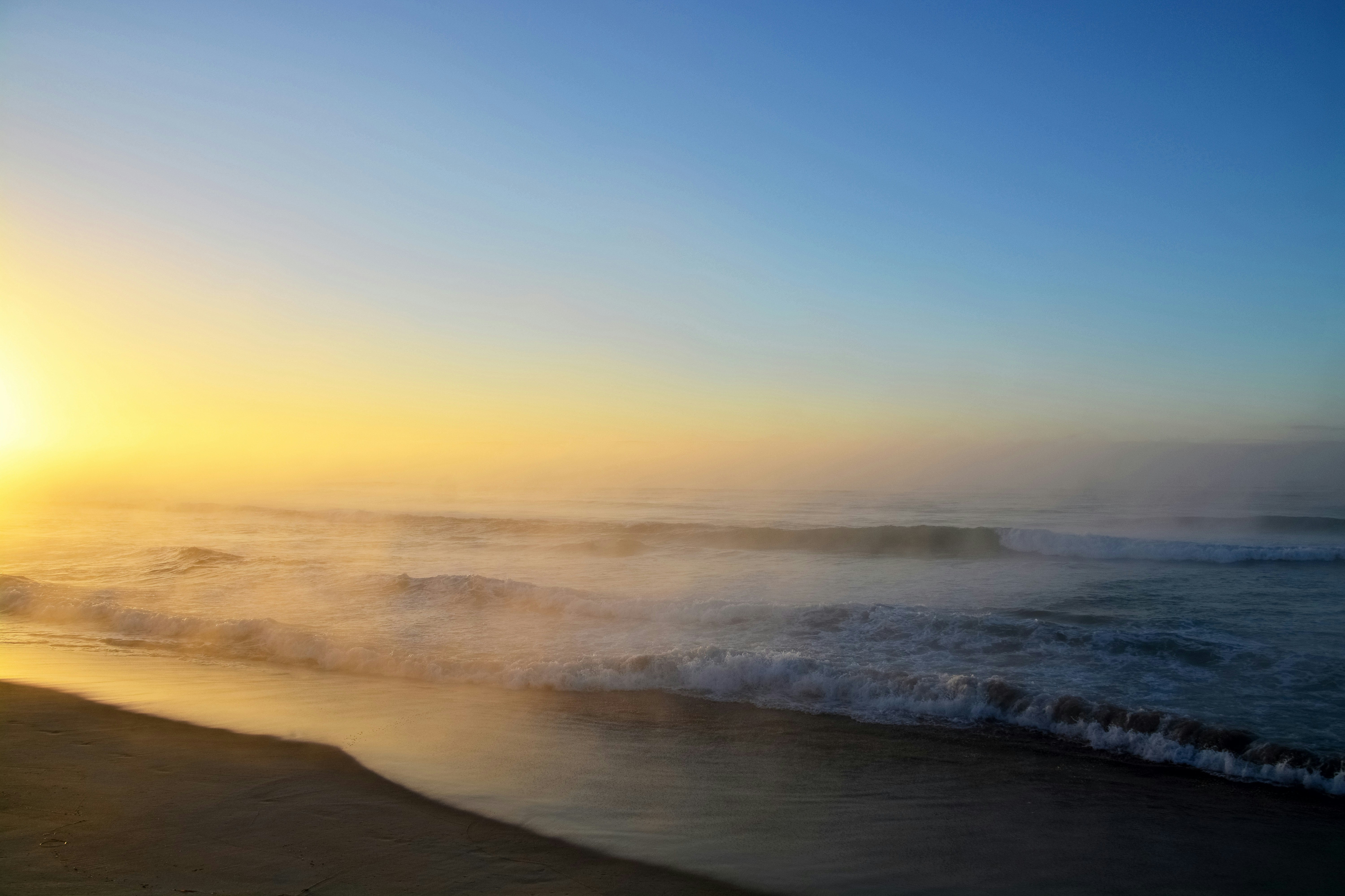 ocean waves crashing on shore during sunset
