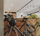 woman in black jacket standing beside blue bicycle