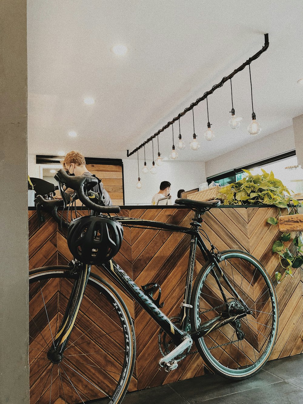 Frau in schwarzer Jacke neben blauem Fahrrad