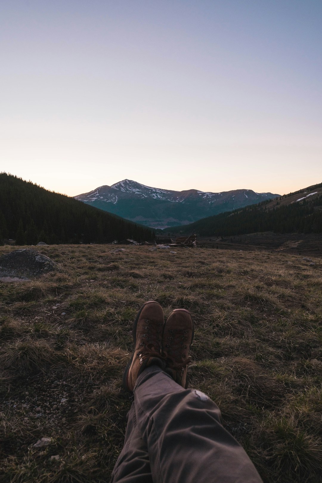 person in brown hiking shoes sitting on brown grass field during daytime