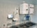 A laboratory setup featuring a water purification system mounted on a tiled wall above a stainless steel double sink. The setup includes two square white units labeled with blue text, and interconnected pipes and blue water filters beneath. A touch screen control panel is installed on the left side with a digital display.