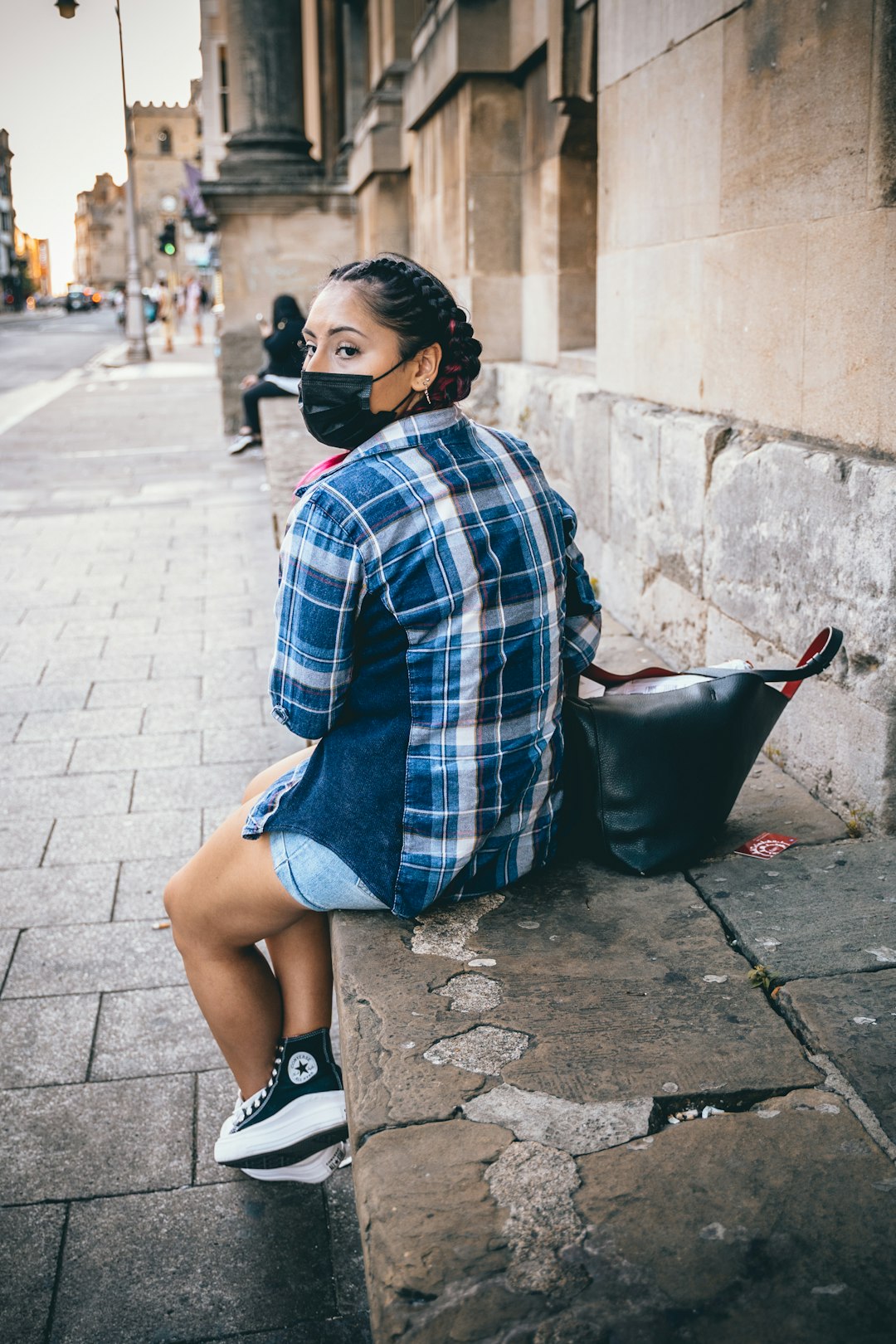 woman in blue and white plaid dress shirt and black pants sitting on concrete bench during