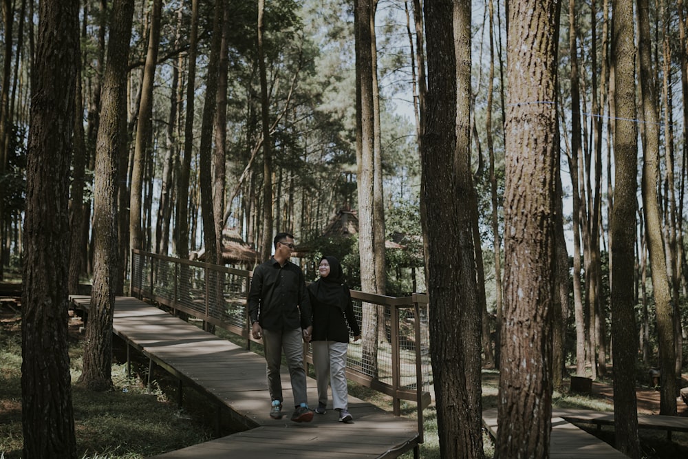 man and woman walking on wooden bridge