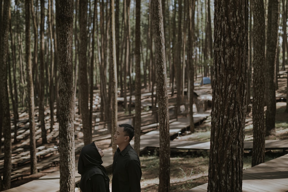 man and woman standing in the middle of the forest during daytime