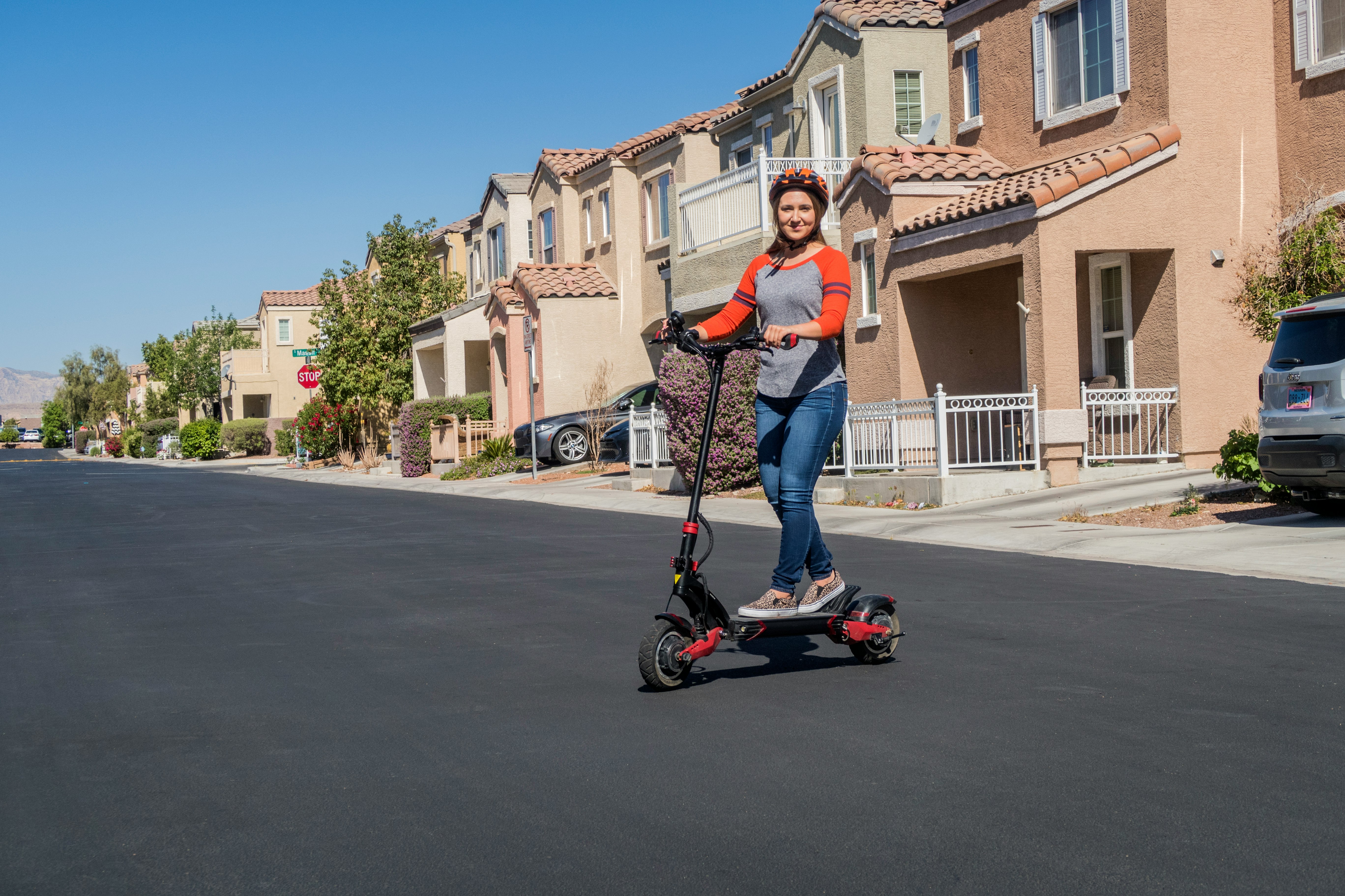 woman in red t-shirt and blue denim jeans riding on red and black kick scooter