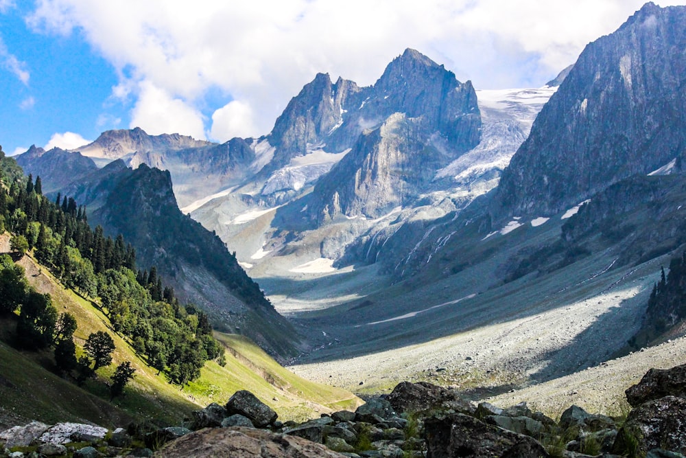 montañas verdes y grises bajo nubes blancas durante el día