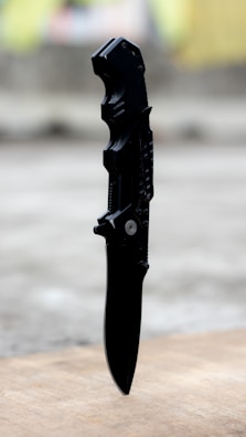 Close-up of a tactical knife on a wooden surface.