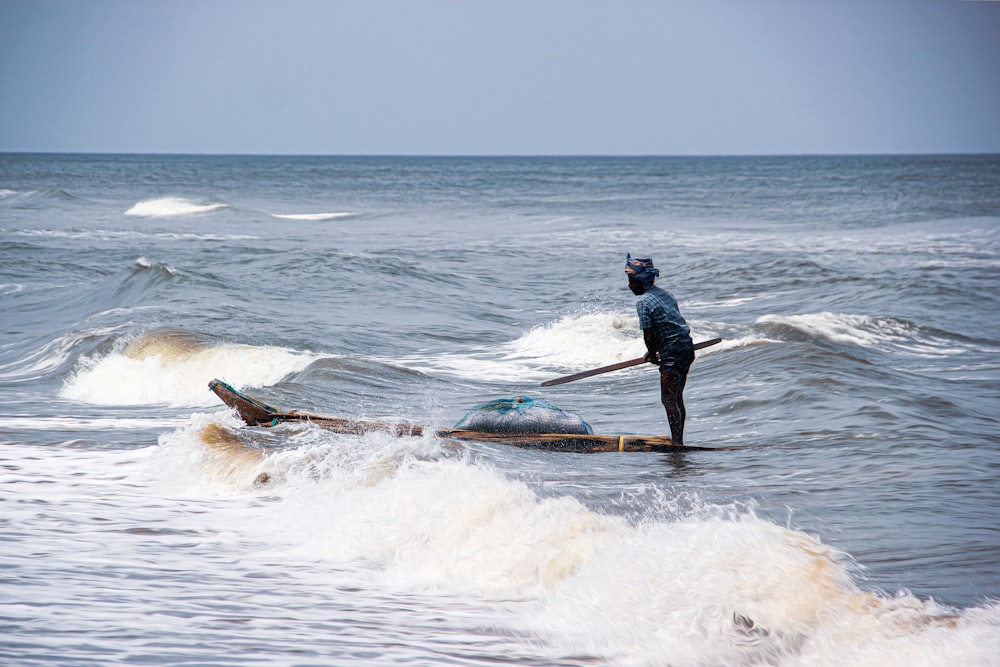 man in blue jacket and black pants surfing on sea waves during daytime