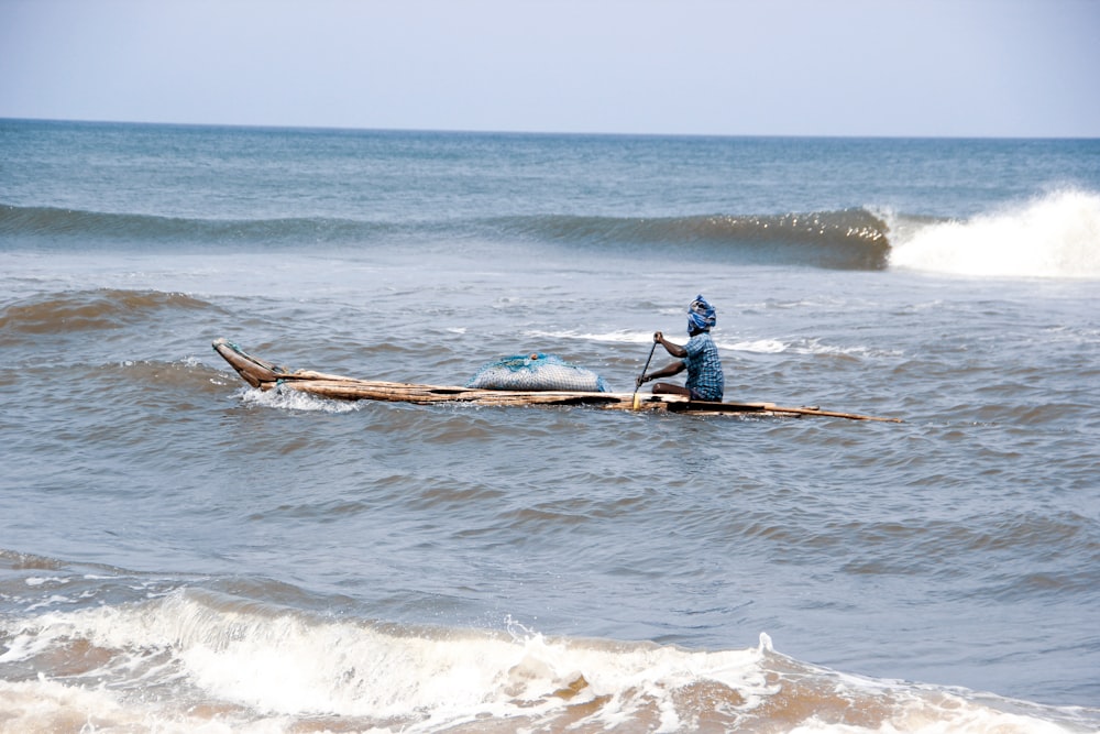 man in black shirt riding on brown wooden boat on sea during daytime