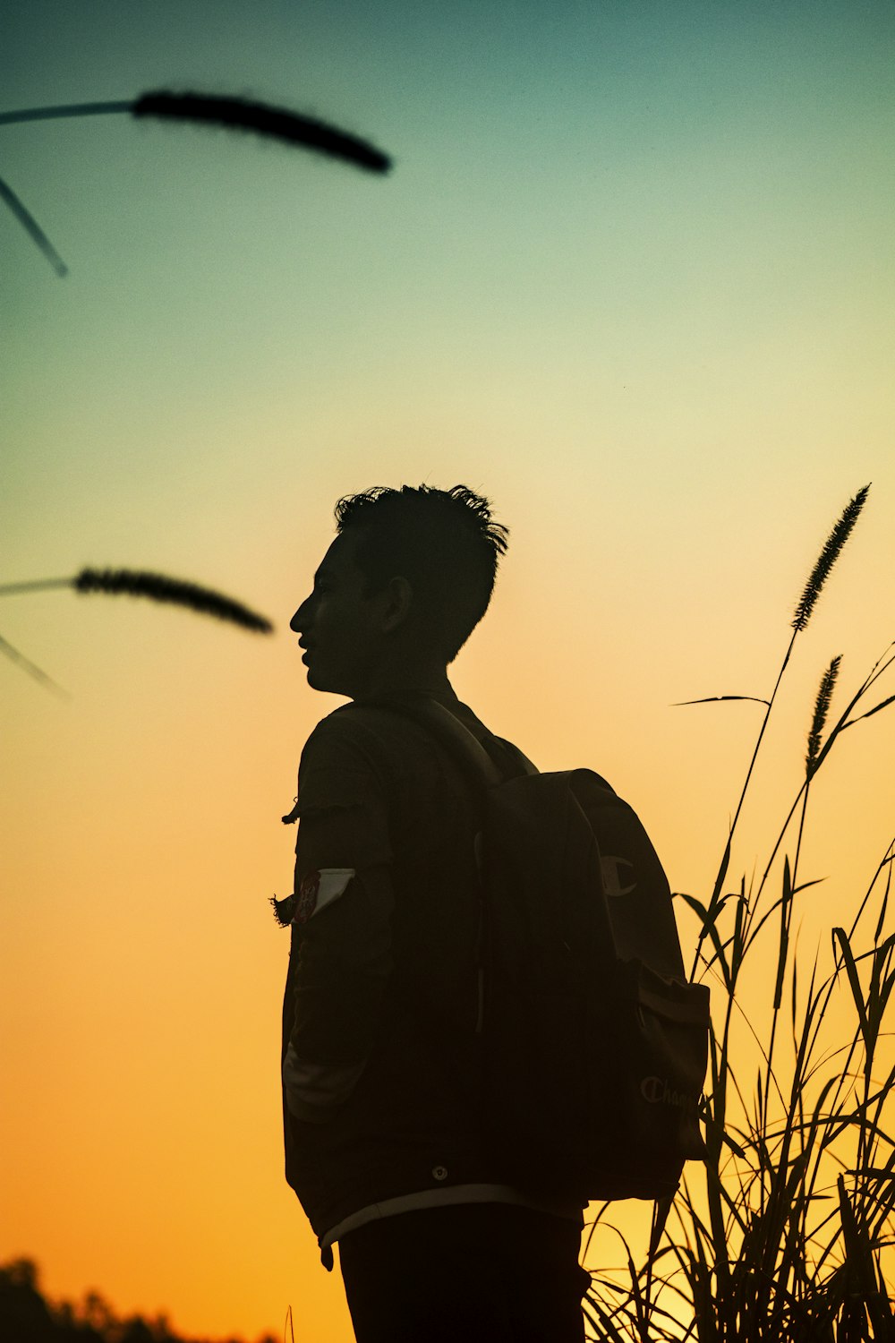 man in black jacket standing on grass field during sunset