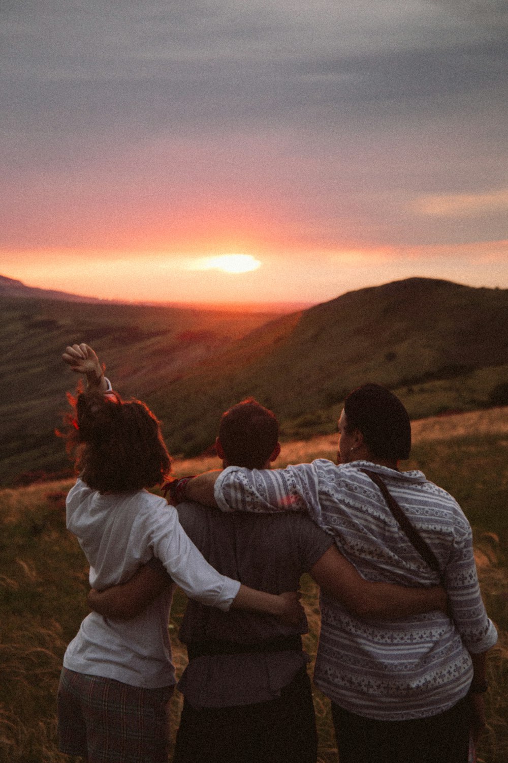 man and woman sitting on grass field during sunset