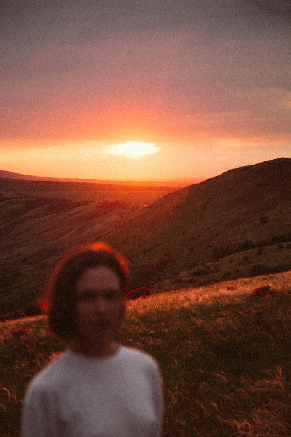 a woman standing on top of a lush green hillside