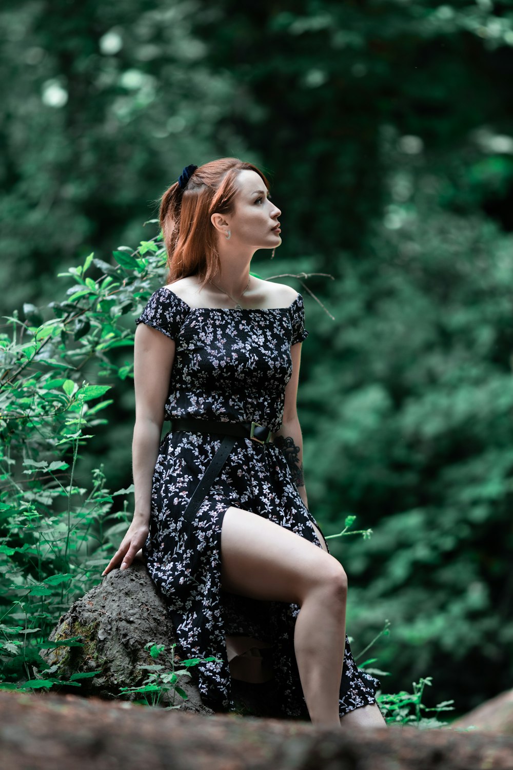 woman in black and white floral dress sitting on rock