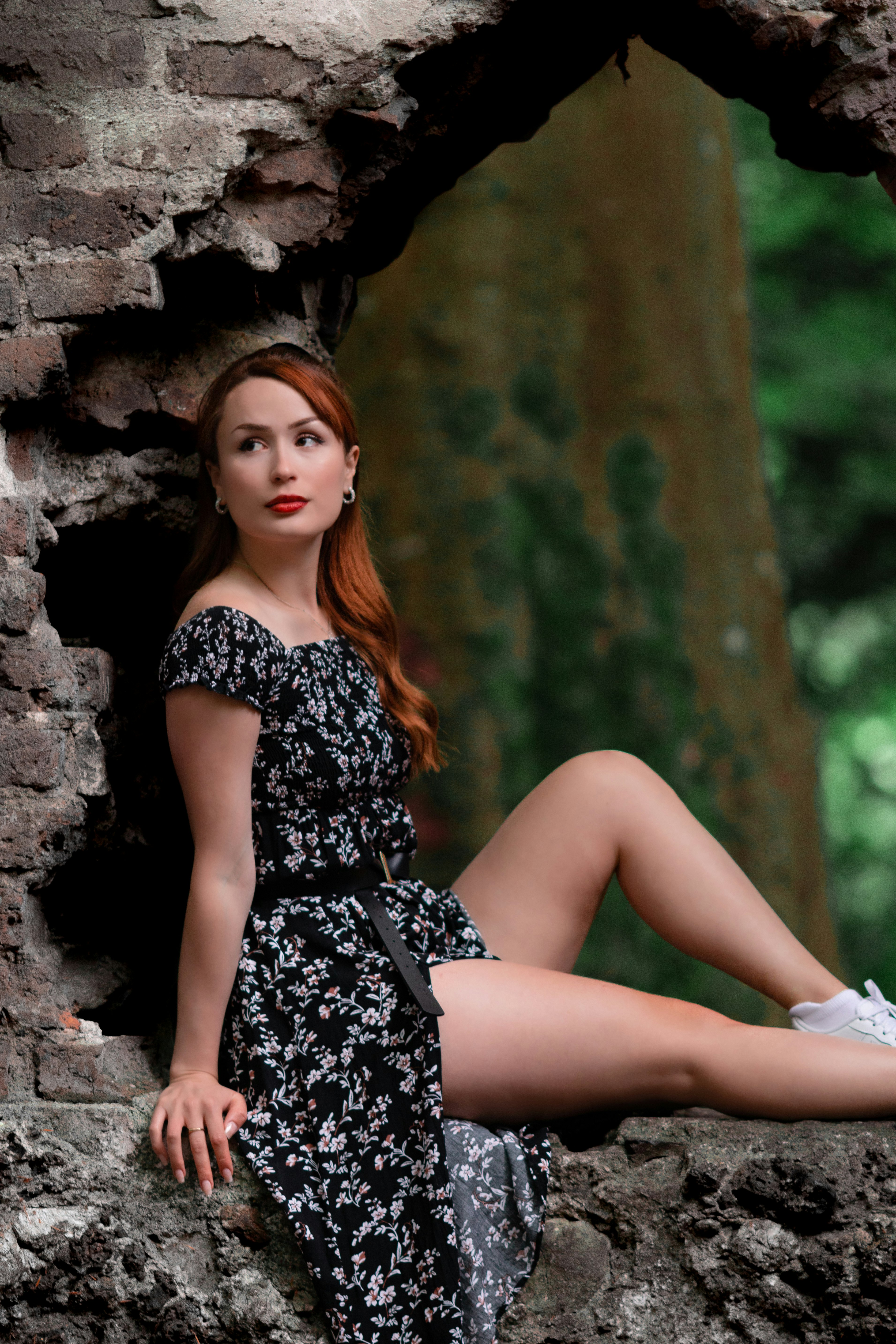 woman in black and white floral dress sitting on rock