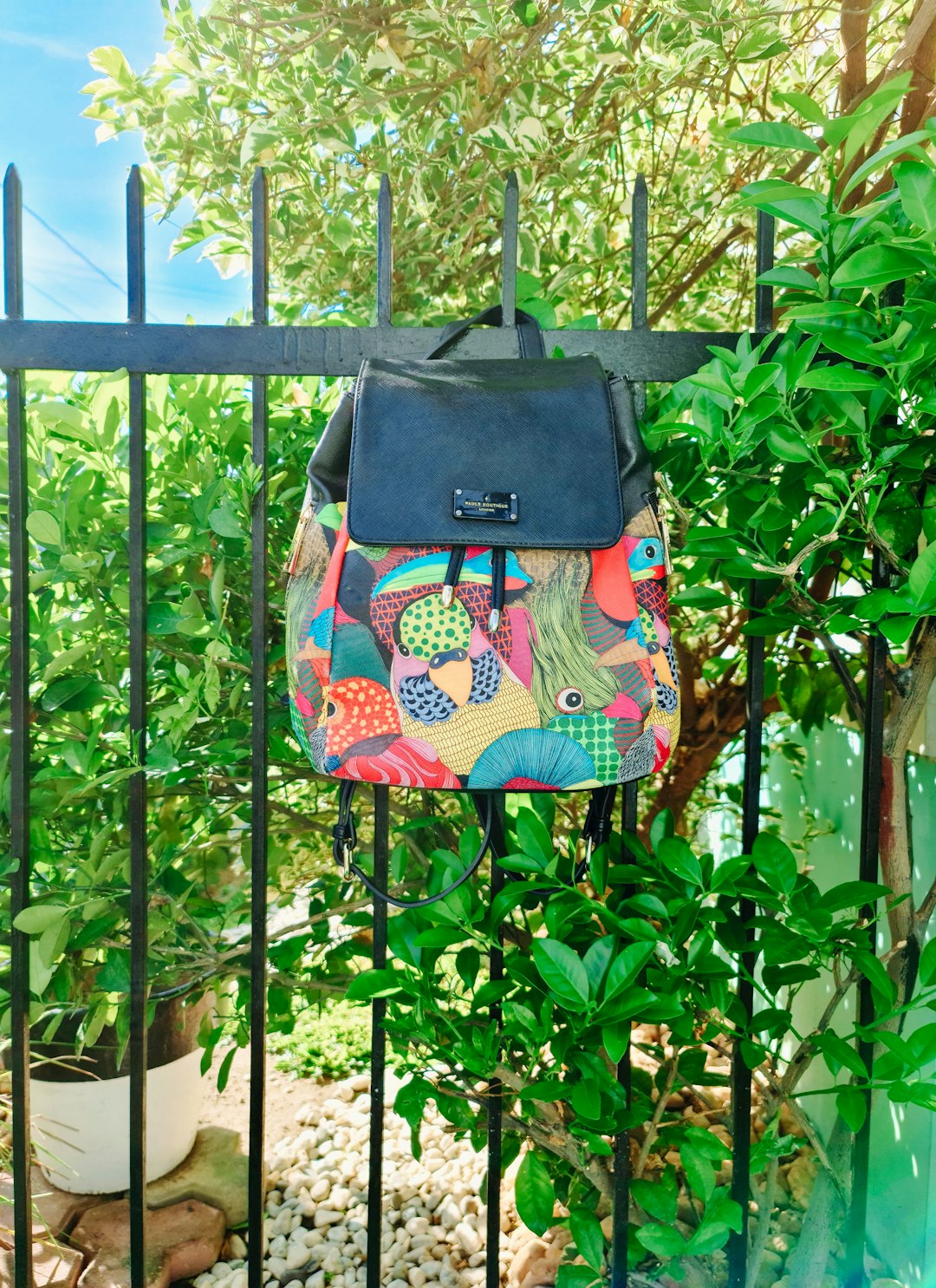 black and pink backpack hanged on green metal fence