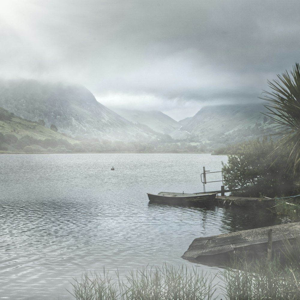 brown wooden dock on lake near green mountains during daytime