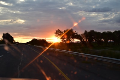 Sunset road trip scene with acoustic guitar resting on a car hood.