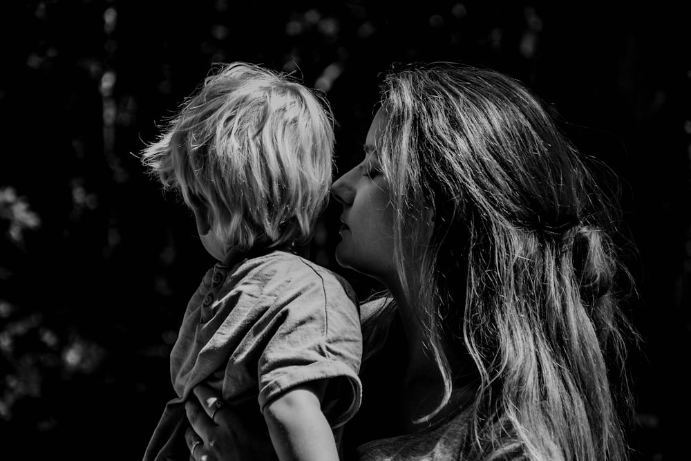 grayscale photo of woman kissing boys cheek