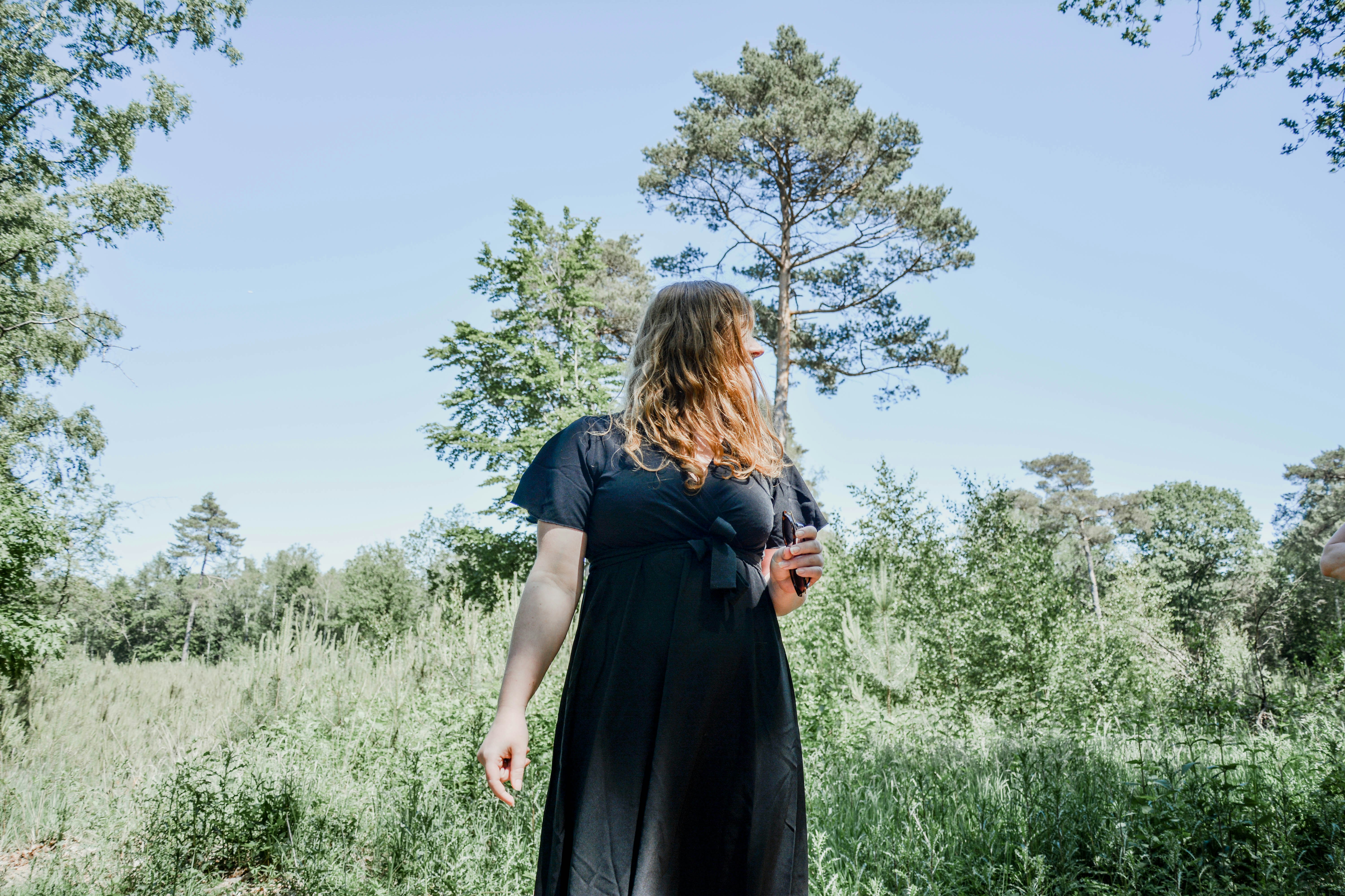 woman in black dress standing on green grass field during daytime
