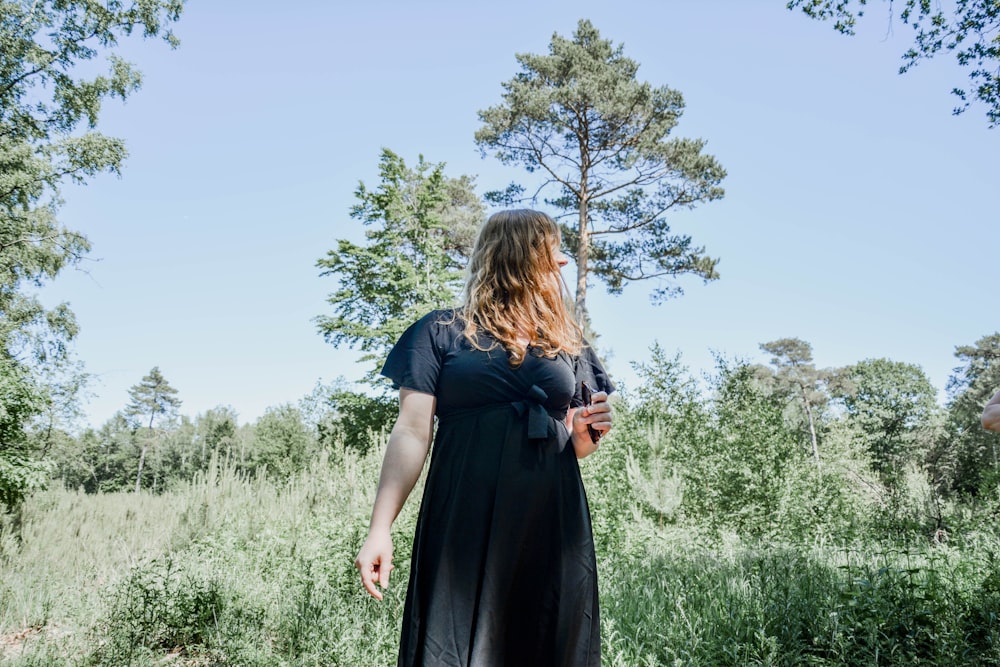 woman in black dress standing on green grass field during daytime