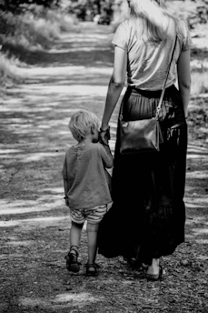 grayscale photo of 2 children walking on beach
