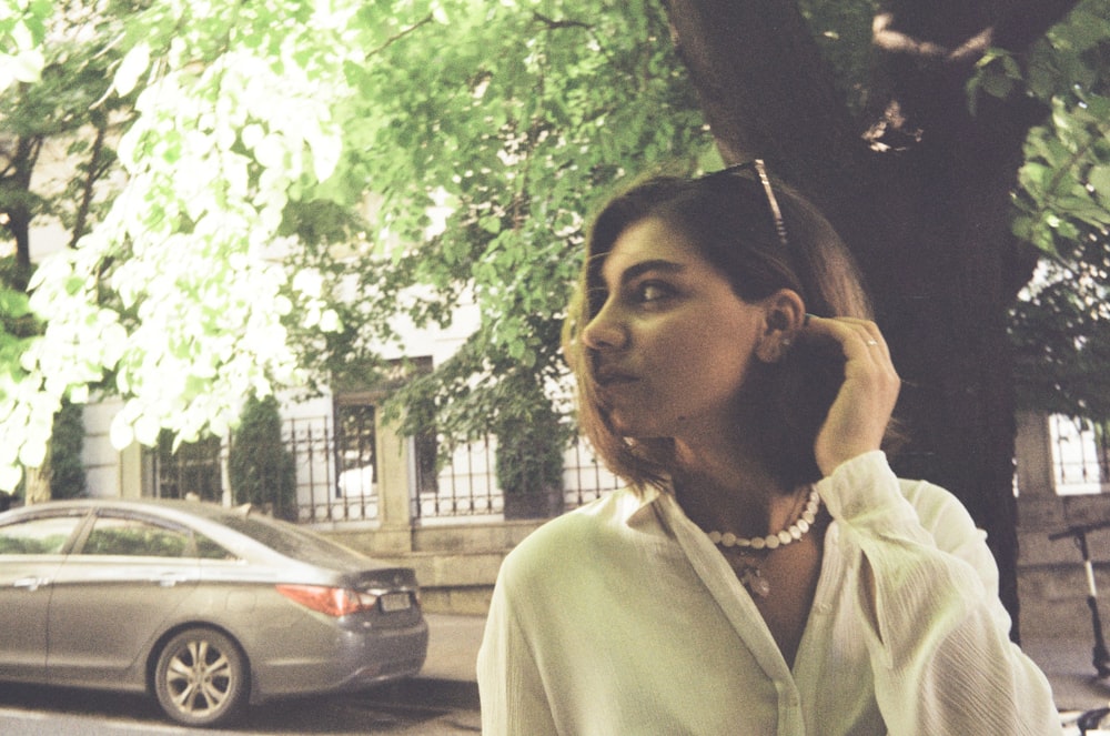 woman in white button up shirt standing near black car during daytime