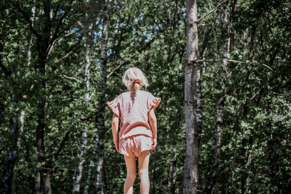woman in orange and white stripe shirt standing in forest during daytime