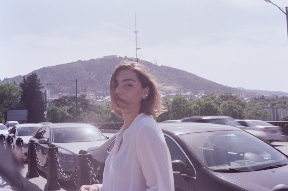 woman in white long sleeve shirt standing beside black car during daytime