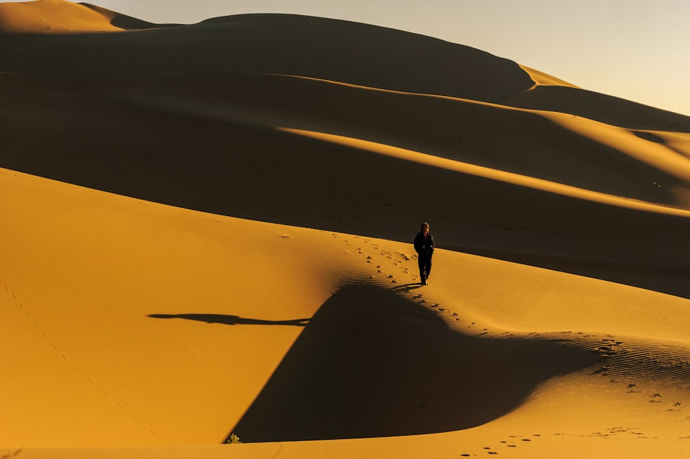 person walking on sand dunes