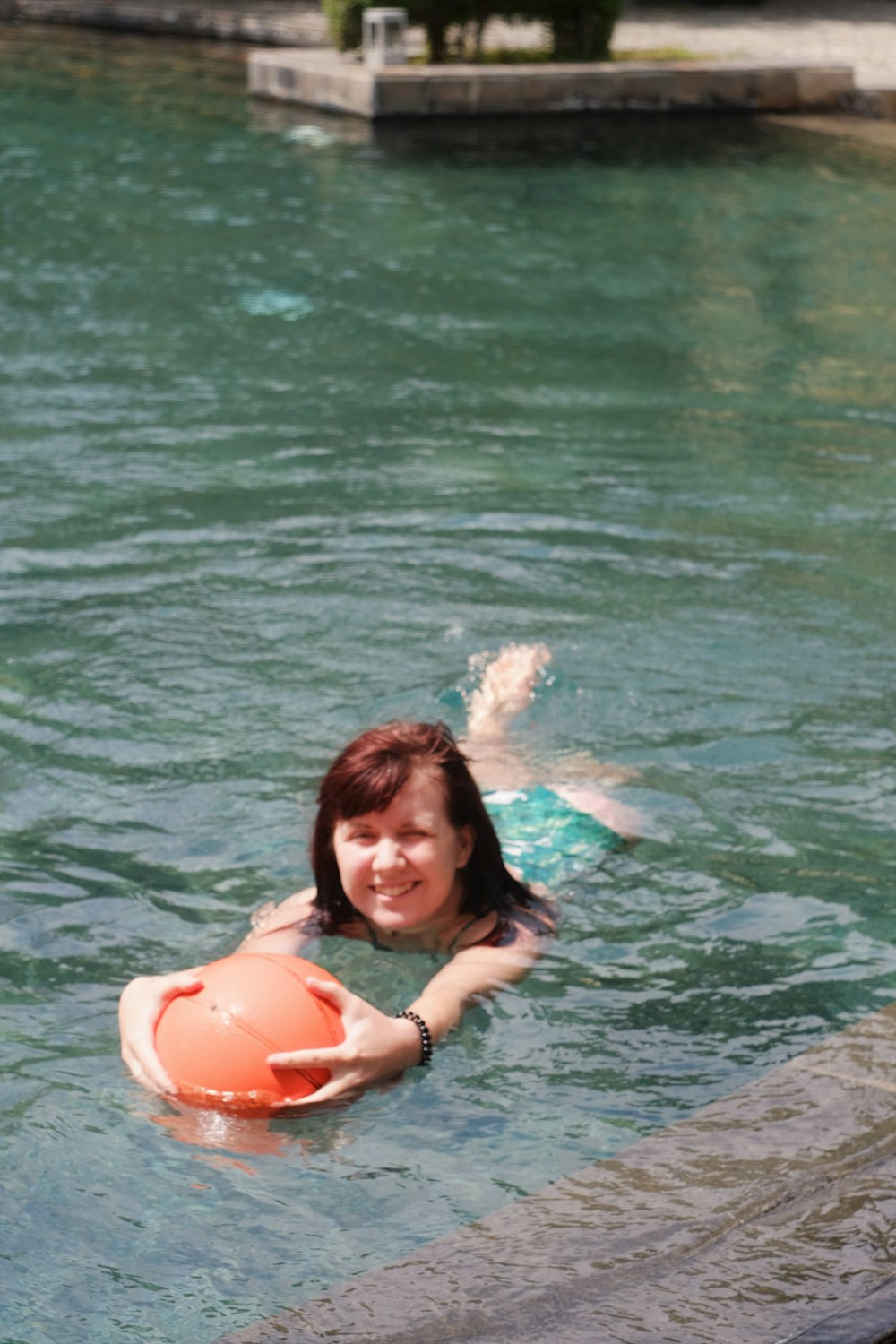 woman in black bikini top on water holding orange inflatable ring