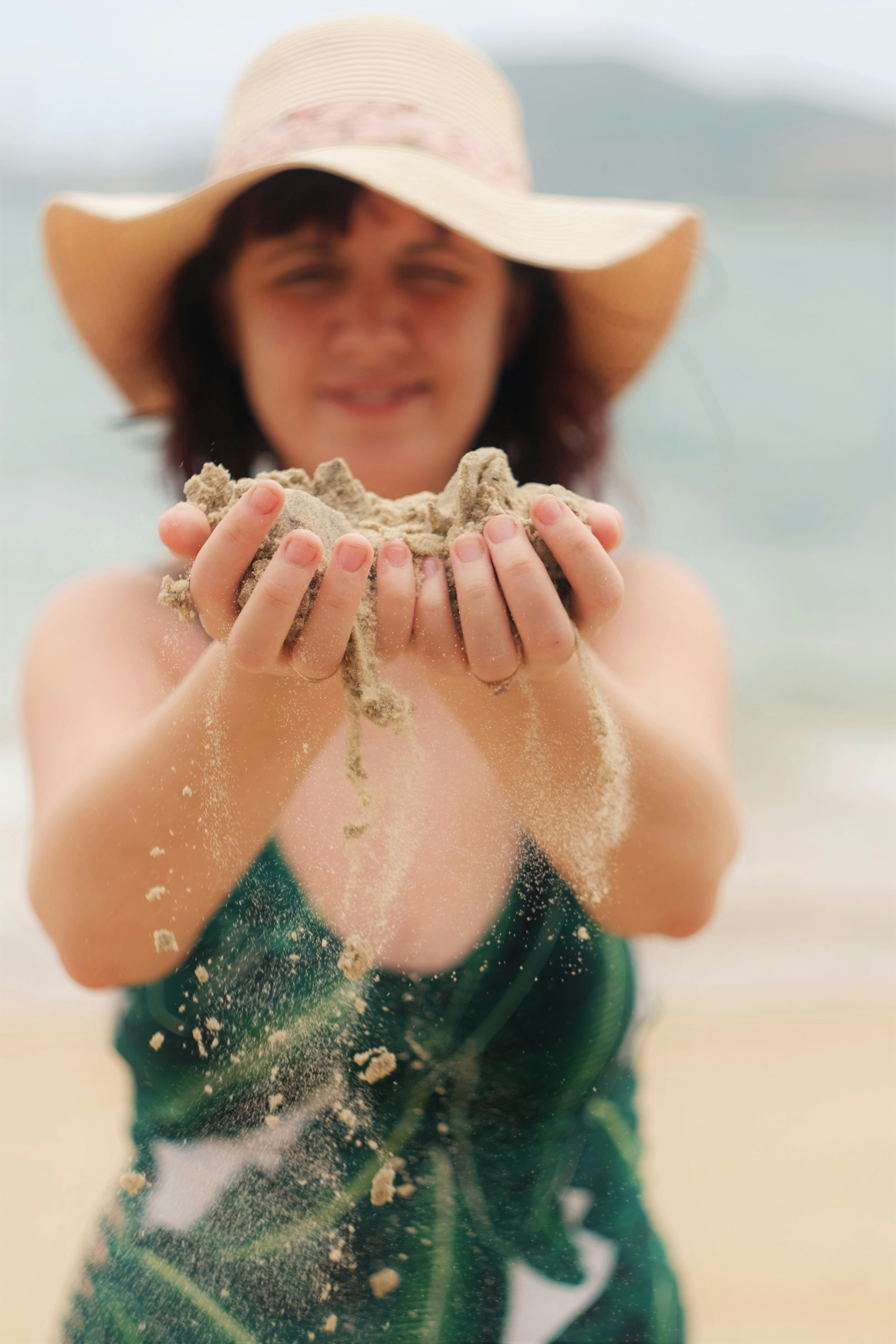 woman in white sun hat holding sand