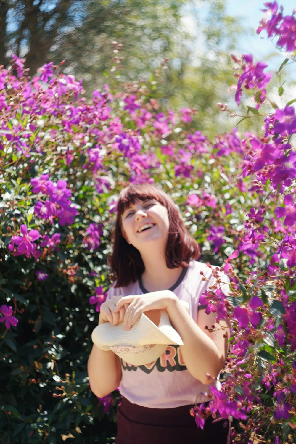 woman in white sleeveless dress standing near pink flowers