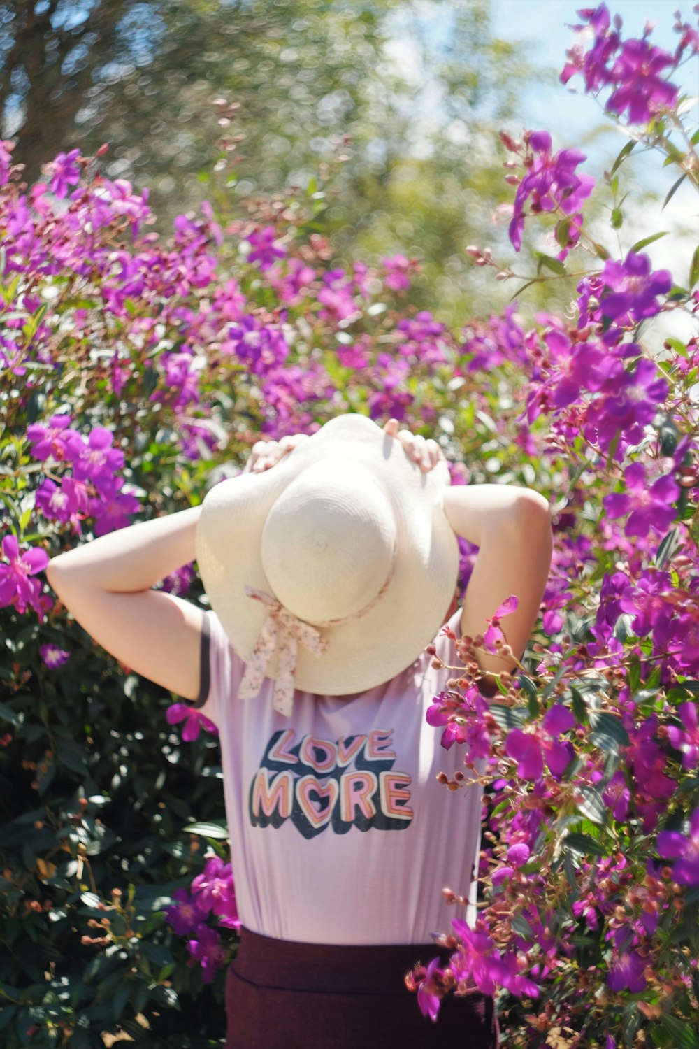 girl in white t-shirt and brown cowboy hat standing on purple flower field during daytime