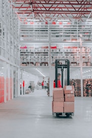 man in black pants and black jacket standing on black and red fork lift