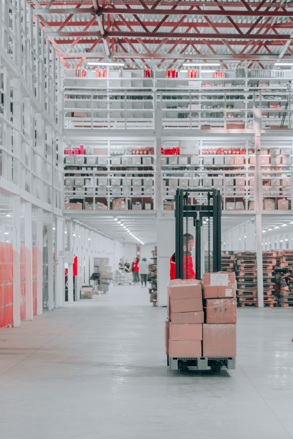 man in black pants and black jacket standing on black and red fork lift