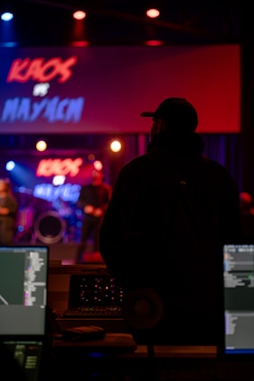 man in black jacket standing in front of audio mixer