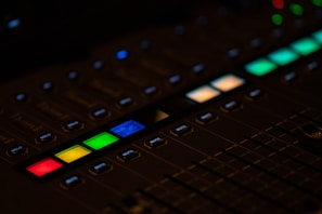 Close-up of a mixing console with illuminated buttons and sliders in low light