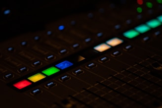 Close-up of a mixing console with illuminated buttons and sliders in low light